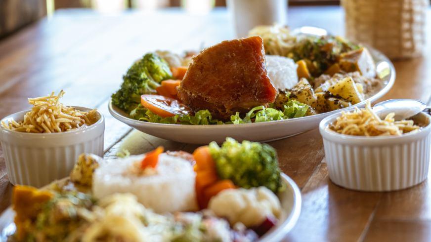 Do Fogão a Lenha ao Coração: A Experiência Gastronômica da Canela de Ema. Por que o jiló empanado e a carne na lata são a nova sensação de 2026 para quem foge da rotina urbana. Viver em cidades como São Paulo, Brasília ou Belo Horizonte é estar em um eterno "modo de espera". Espera pelo trânsito, pelo prazo, pelo descanso. Quando você decide sair desses grandes centros, o seu paladar busca algo que o asfalto não oferece: verdade. Na Cachoeira Canela de Ema, a gastronomia não é um complemento; é o prato principal. Nossa cozinha é um tributo à Serra da Canastra. Fomos destaque no Festival Gastronômico Sabores de Capitólio por um motivo simples: respeitamos o tempo dos ingredientes. Nossa Carne na Lata, agora com selo SIM para comercialização em escala, é feita como o Seu José Leonel fazia na Fazenda Tamboretes na década de 60. É o pernil de porco conservado na própria banha, resultando em uma maciez que nenhuma técnica moderna consegue replicar.